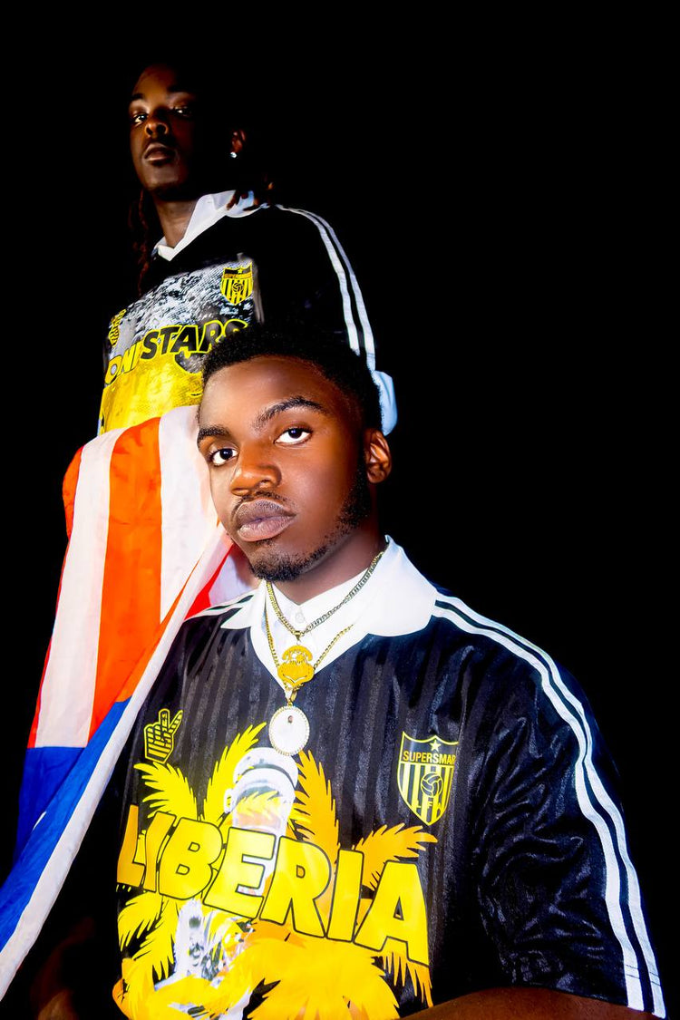 Two models wearing black-and-gold SuperSmartLIB Liberian Flag Day jerseys with a Liberian flag